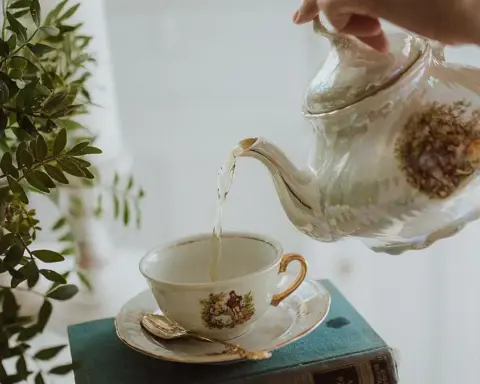 Tea being poured from a porcelain teapot into a small cup and saucer