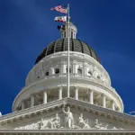 The dome and pediment of the California State Capitol building in Sacramento against a blue sky