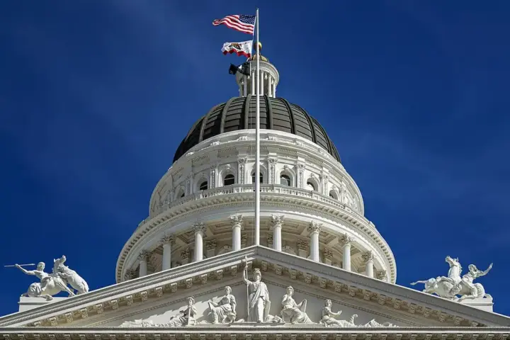 The dome and pediment of the California State Capitol building in Sacramento against a blue sky