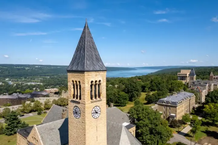 High-angle daytime perspective of McGraw Clock Tower surrounded by academic buildings and trees on the Cornell University campus