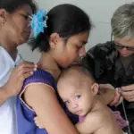 Healthcare physician using a medical stethoscope to listen to an infant chest and lungs during an examination.