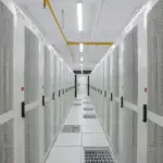 Rows of illuminated enterprise computer servers and network cables inside a modern cloud computing data center.