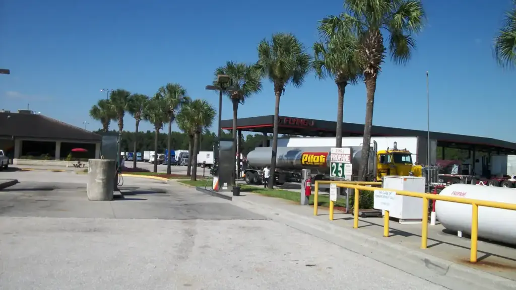 Side view of a large semi-truck tractor unit at a diesel fueling station bay with fuel nozzles