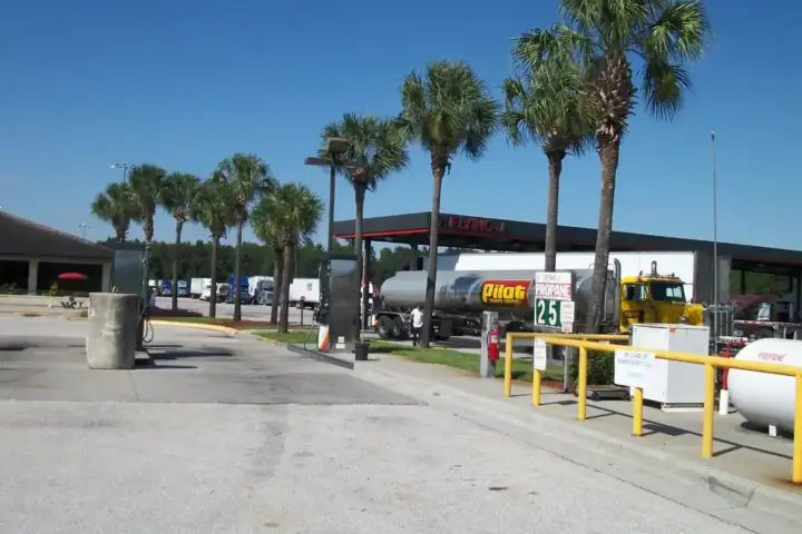 Side view of a large semi-truck tractor unit at a diesel fueling station bay with fuel nozzles