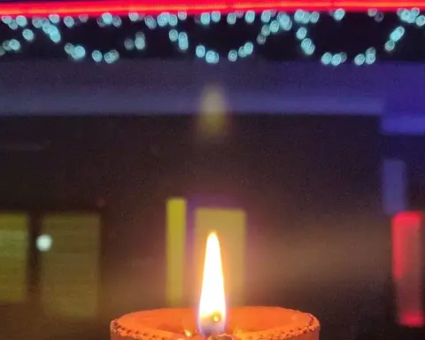 A residential home decorated with strings of LED lights and rows of traditional clay diya lamps illuminating the entrance for Diwali