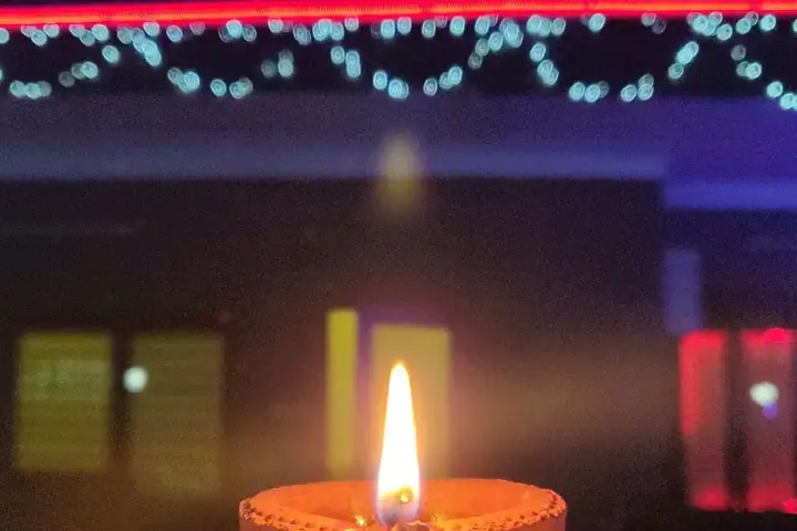 A residential home decorated with strings of LED lights and rows of traditional clay diya lamps illuminating the entrance for Diwali