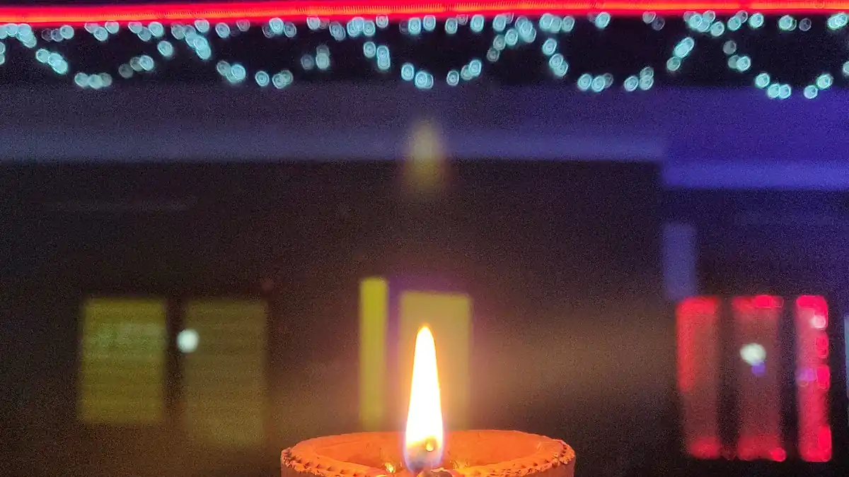A residential home decorated with strings of LED lights and rows of traditional clay diya lamps illuminating the entrance for Diwali