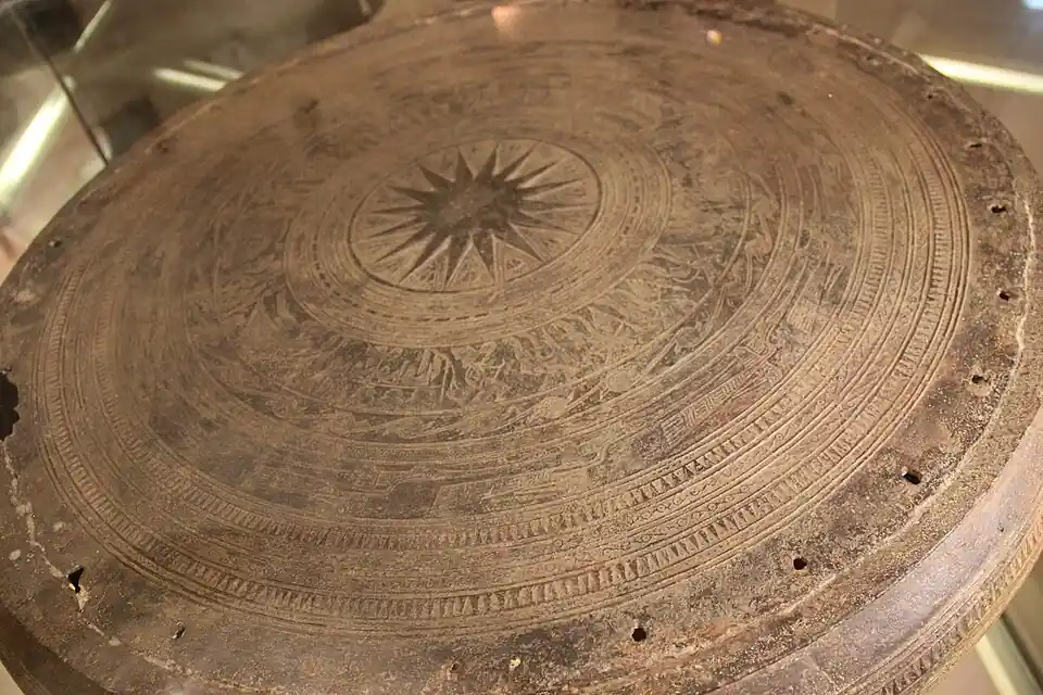 Detailed view of an ancient Vietnamese bronze drum displaying geometric patterns and central sunburst motifs.