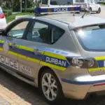 A white and blue South African Police Service patrol car parked on a city street in Durban, South Africa.