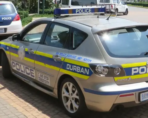A white and blue South African Police Service patrol car parked on a city street in Durban, South Africa.