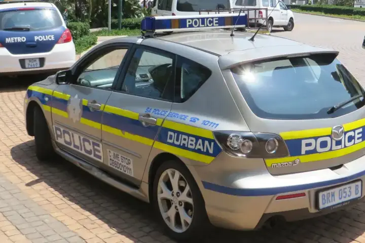 A white and blue South African Police Service patrol car parked on a city street in Durban, South Africa.