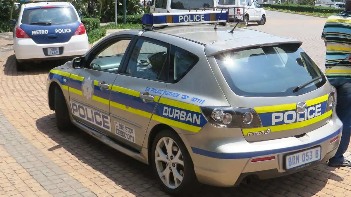 A white and blue South African Police Service patrol car parked on a city street in Durban, South Africa.