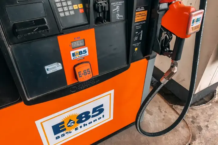 Detailed view of an E85 85 percent ethanol fuel pump nozzle and dispenser panel at an automotive service station.