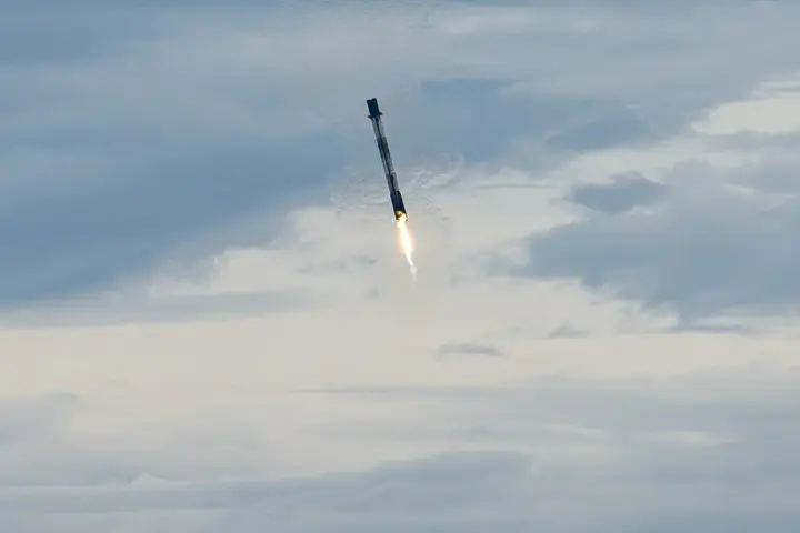 Dramatic high-resolution photograph of a SpaceX Falcon 9 first-stage orbital booster landing vertically on its landing legs amidst smoke at Cape Canaveral.
