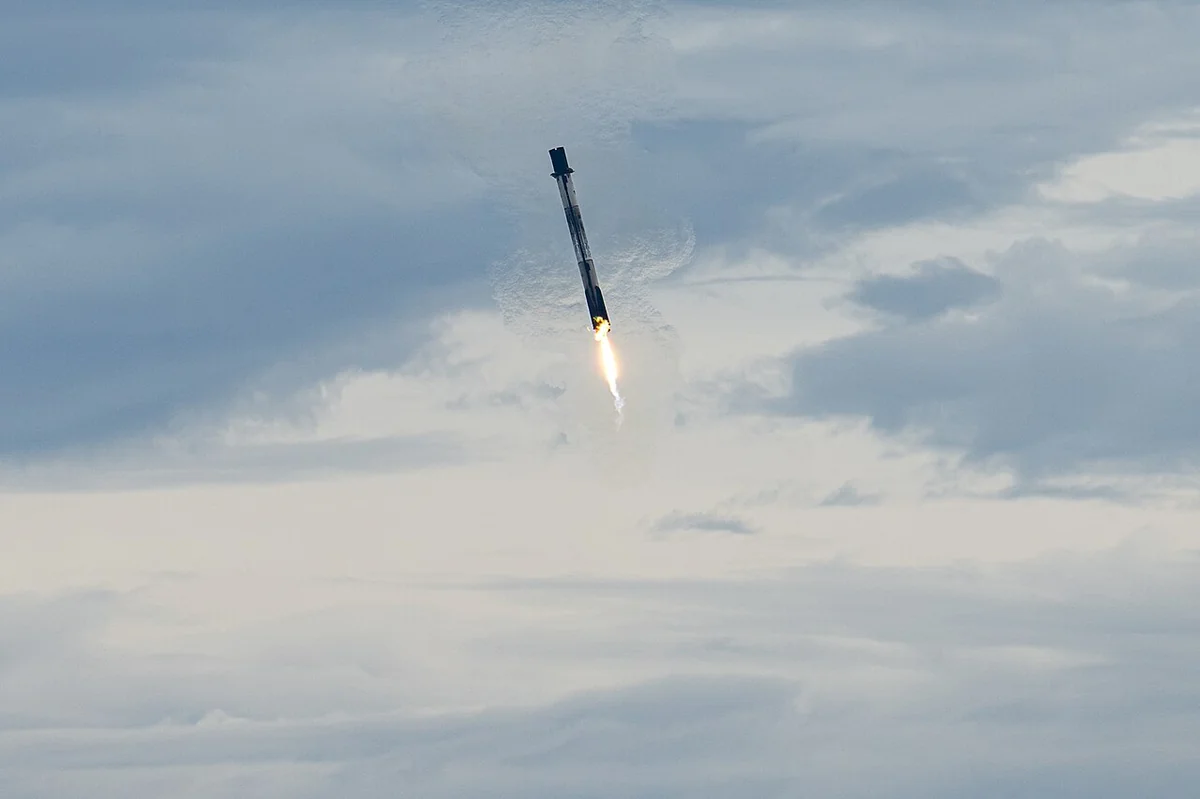 Dramatic high-resolution photograph of a SpaceX Falcon 9 first-stage orbital booster landing vertically on its landing legs amidst smoke at Cape Canaveral.