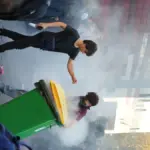 French students attempt to extinguish a burning bin during a school blockade protest