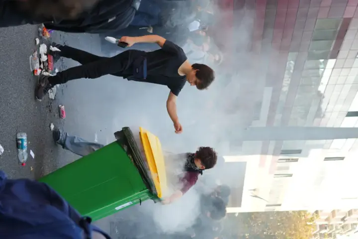 French students attempt to extinguish a burning bin during a school blockade protest