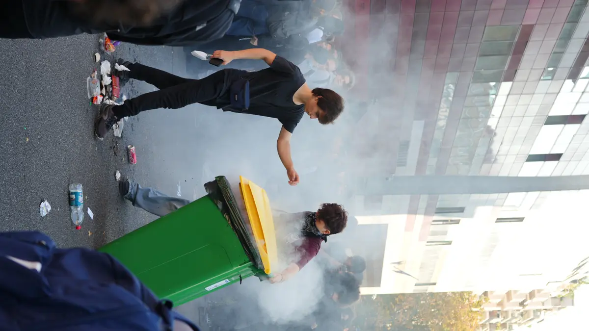 French students attempt to extinguish a burning bin during a school blockade protest