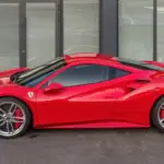 Red Ferrari 488 GTB sports car parked on asphalt, showing glossy paint, alloy wheels, and natural daylight reflections.