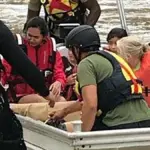 Emergency rescue workers in a boat evacuating people from fast-rising flash flood water