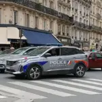 French National Police vehicles and crowd control units positioned along an urban street during a public protest.