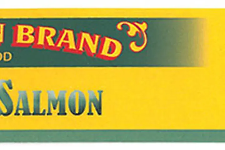 Rows of canned tuna and fruit cocktail products on a grocery store shelf marked for recall