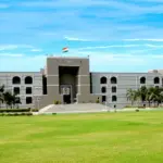 Front architectural view of the Gujarat High Court judicial complex in Ahmedabad under an open sky.