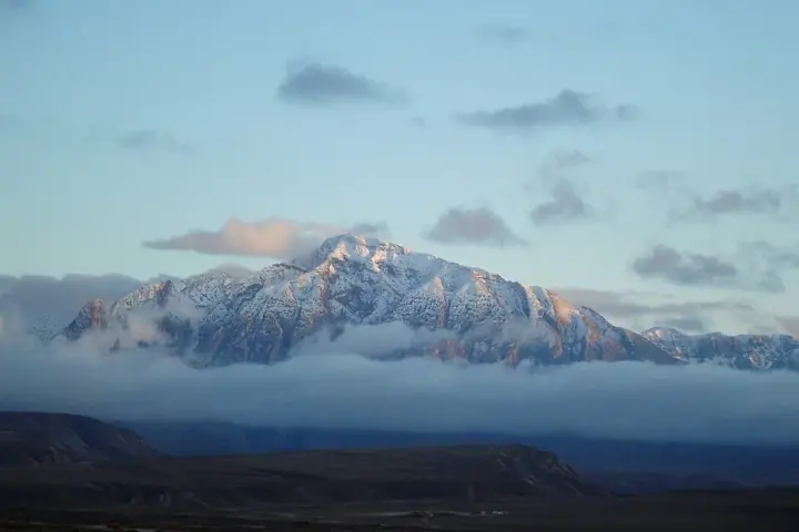 Panoramic view of the arid, snow-dusted peaks of the Hindu Kush mountain range rising into the sky.