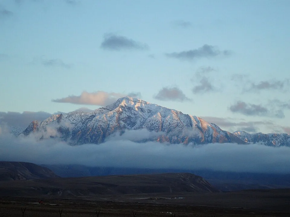 Panoramic view of the arid, snow-dusted peaks of the Hindu Kush mountain range rising into the sky.