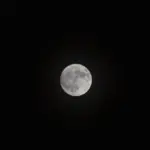 Detailed close-up photograph of the full Moon's cratered surface against a dark night sky.