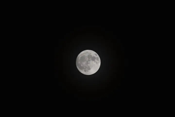 Detailed close-up photograph of the full Moon's cratered surface against a dark night sky.