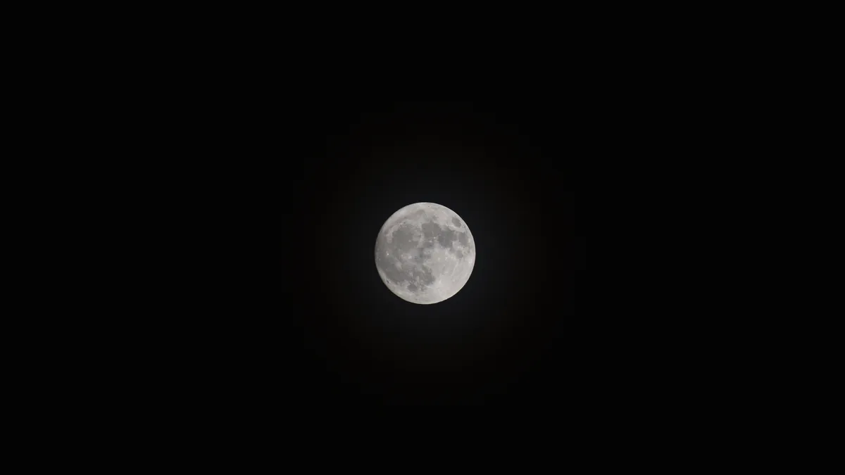 Detailed close-up photograph of the full Moon's cratered surface against a dark night sky.