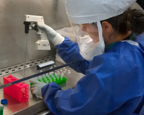 Researcher handling clinical vials and a precision pipette during peptide testing.
