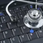 Laptop computer and stethoscope representing digital health data management in hospitals.
