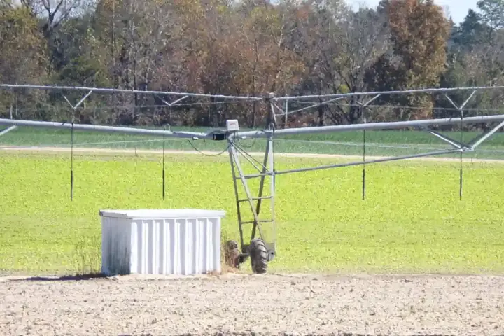 Sprinkler irrigation system spraying water over farmland fields in a precision agriculture setup