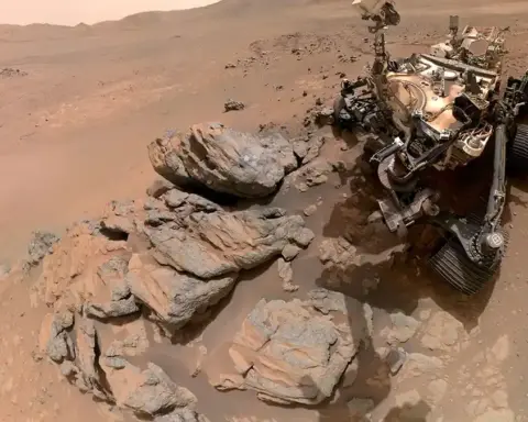 Photograph of NASA's Perseverance Mars rover beside rock outcrops on the surface of Jezero Crater during its dust analysis mission