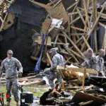 Ground emergency crews clearing fallen trees and structural debris in a storm-damaged North Carolina neighborhood