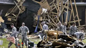 Ground emergency crews clearing fallen trees and structural debris in a storm-damaged North Carolina neighborhood