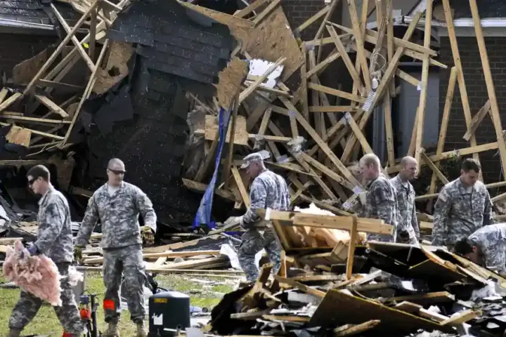 Ground emergency crews clearing fallen trees and structural debris in a storm-damaged North Carolina neighborhood