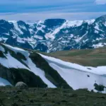 A highway corridor through snow-covered mountain terrain in the Rocky Mountains.