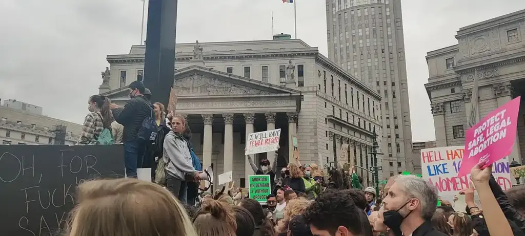 Large crowd of demonstrators gathered in lower Manhattan civic plaza holding signs and rallying for institutional accountability and survivor rights.