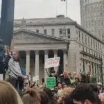 Large crowd of demonstrators gathered in lower Manhattan civic plaza holding signs and rallying for institutional accountability and survivor rights.