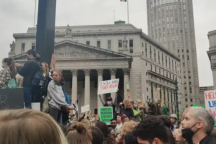 Large crowd of demonstrators gathered in lower Manhattan civic plaza holding signs and rallying for institutional accountability and survivor rights.