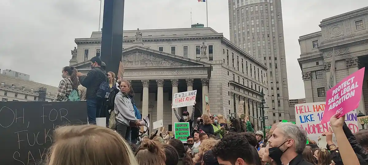 Large crowd of demonstrators gathered in lower Manhattan civic plaza holding signs and rallying for institutional accountability and survivor rights.