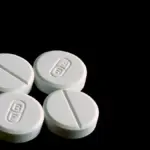 White 500-milligram acetaminophen tablets displayed on a clean reflective surface.