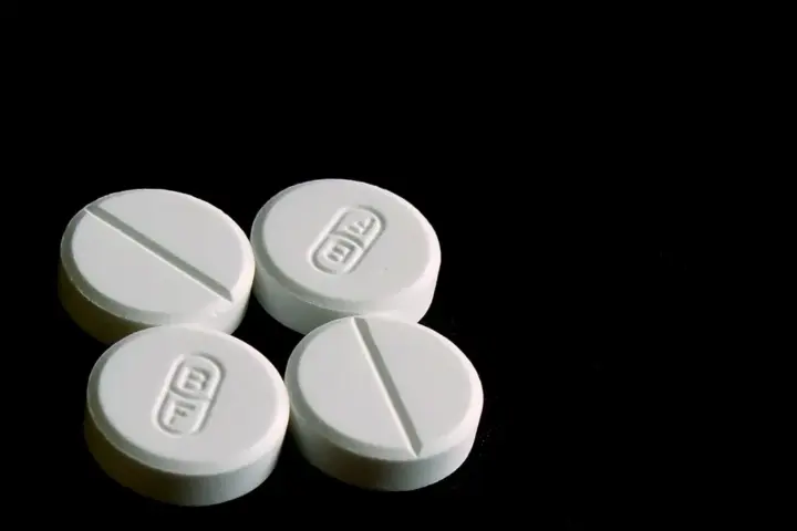 White 500-milligram acetaminophen tablets displayed on a clean reflective surface.