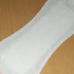A single white absorbent cotton panty liner product displayed unfolded against a clean background.