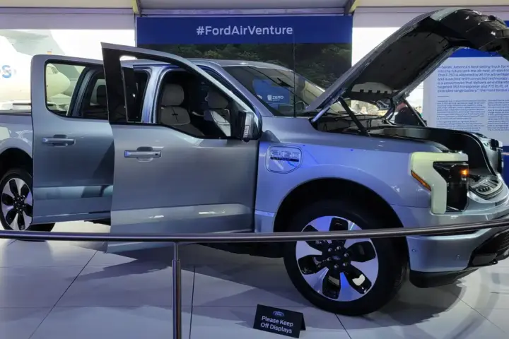 Front three-quarter view of a dark Ford F-150 Lightning all-electric pickup truck parked outdoors.