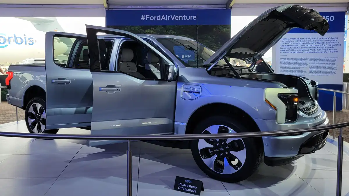 Front three-quarter view of a dark Ford F-150 Lightning all-electric pickup truck parked outdoors.