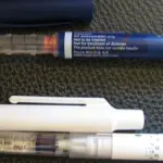 A medical subcutaneous injection pen resting horizontally on a clean surface.